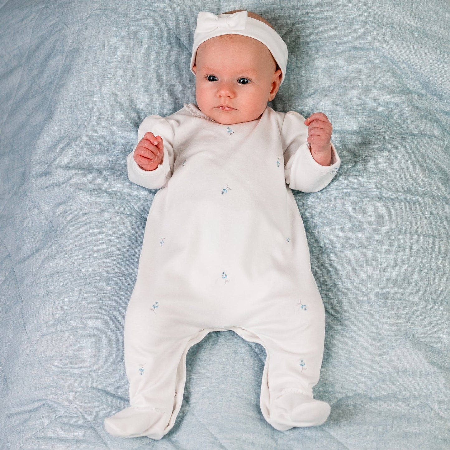 white cotton footed babygrow with blue embroidered rosebuds and a coordinating white hairband with bow